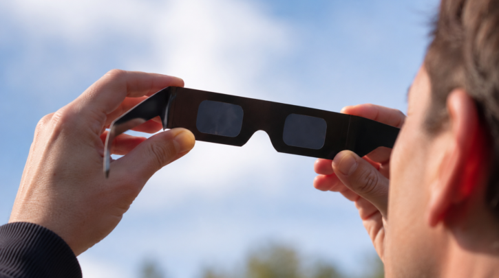 A person putting on certified eclipse glasses before viewing the sun